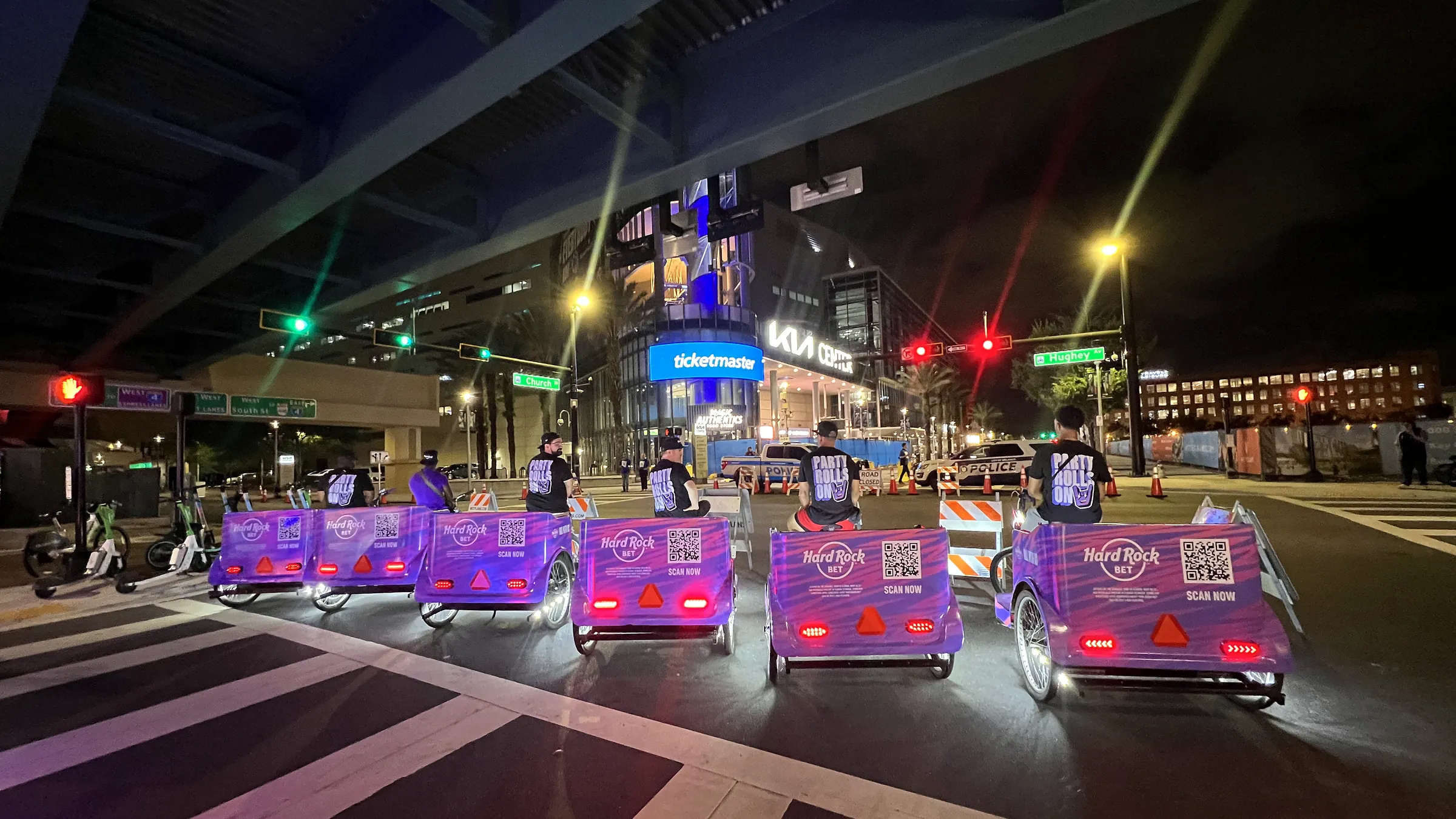 Lit Hard Rock Bet branded Kween Cab pedicab fleet at night in downtown Orlando