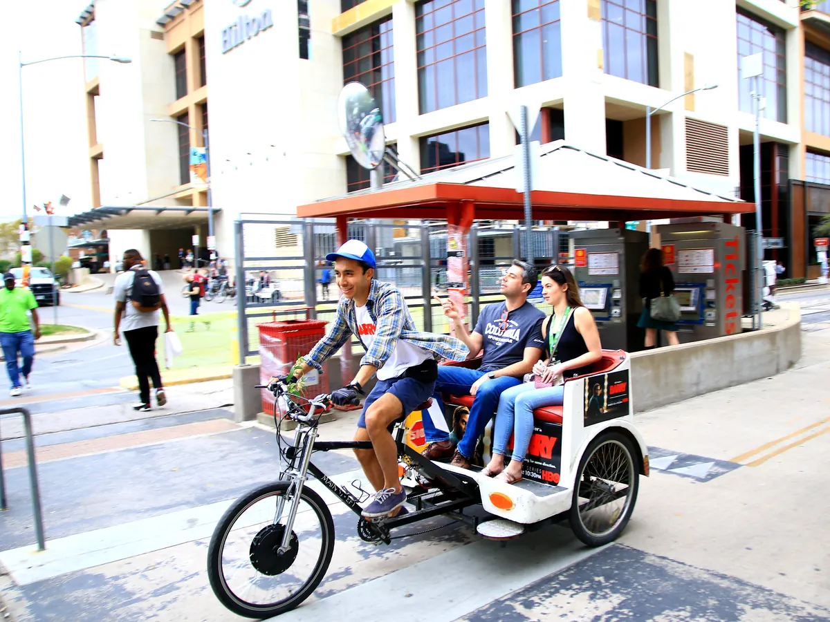 HBO Barry branded Kween Cab pedicab with riders near the MetroRail station in downtown Austin