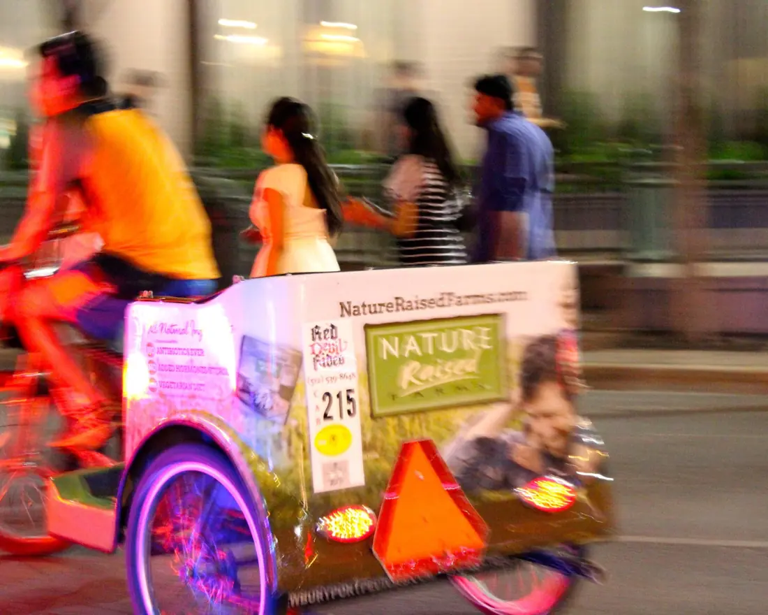Branded pedicab moving through a night festival