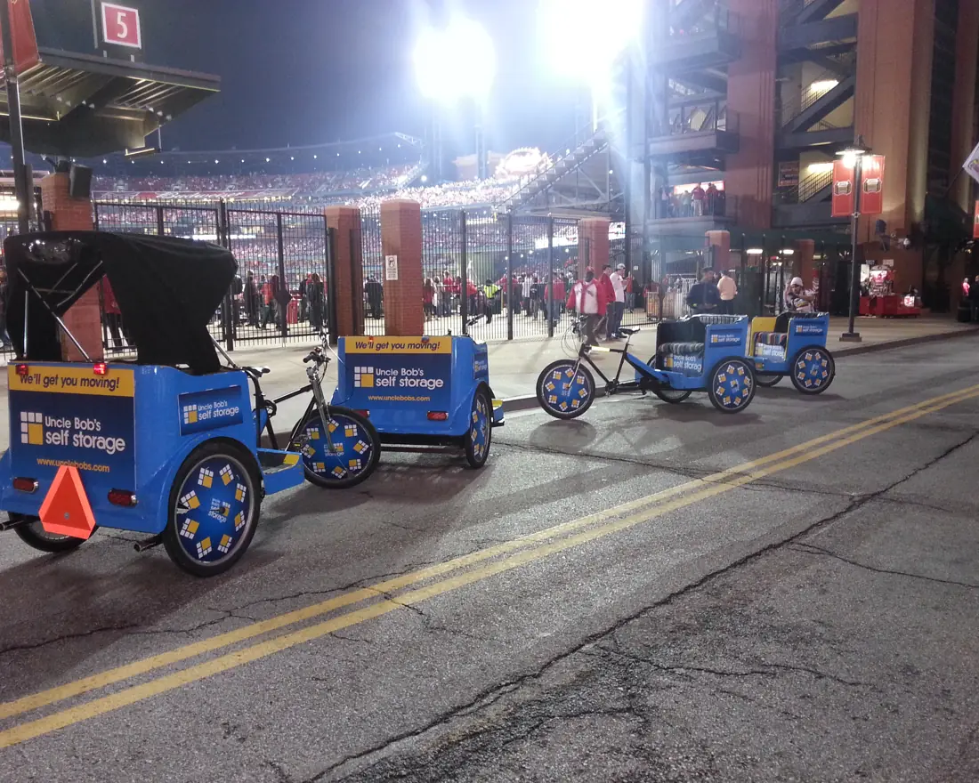 Branded pedicabs on a stadium street at night