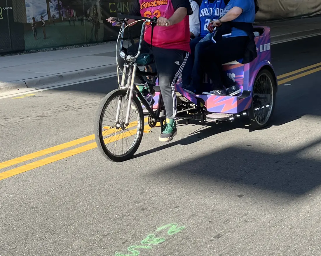Fans in team jerseys riding a Hard Rock Bet pedicab