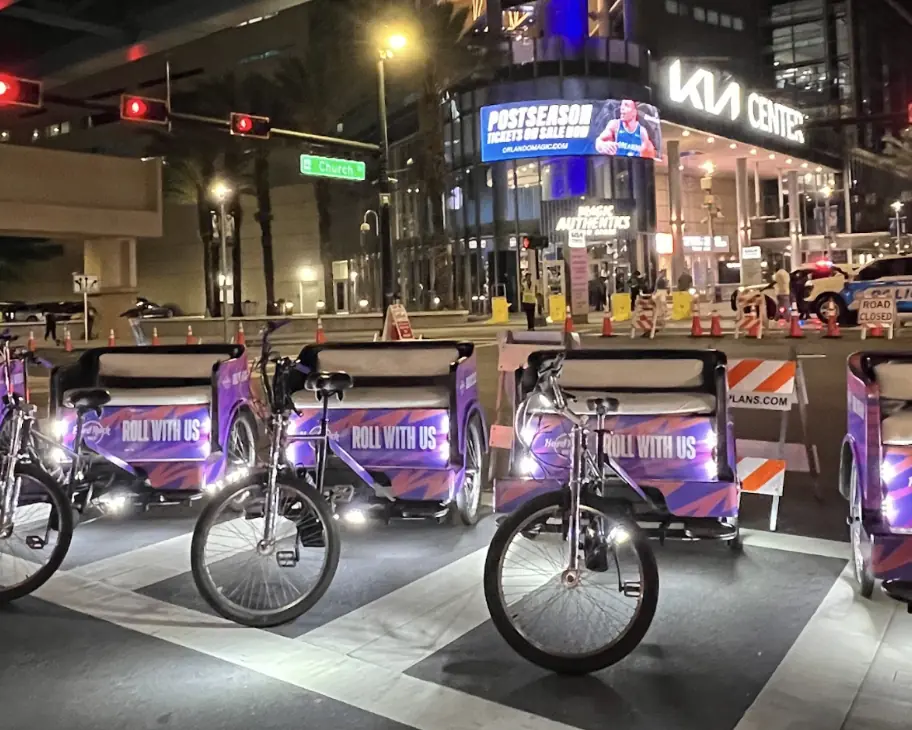Hard Rock Bet “Roll With Us” pedicabs lined up outside the Kia Center in Orlando at night